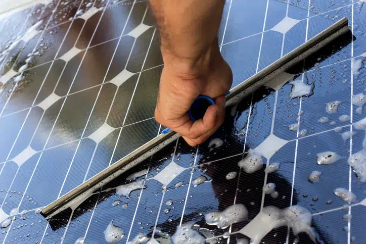 A close shot of soapy water being cleaned by a wiper in solar panels