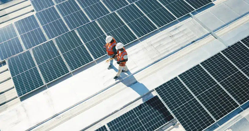 Overhead shot of two technicians with white hard hat walking on solar panels