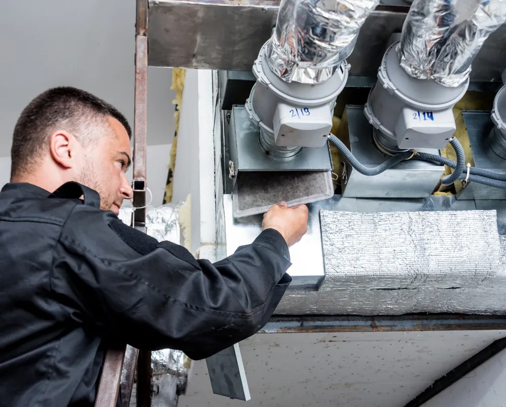 Man inspecting air filter in HVAC duct.