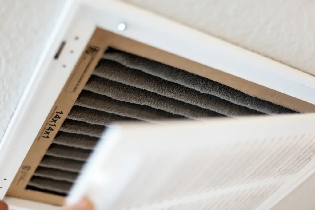 Close-up of dirty 14x14x1 air filter being removed from air vent