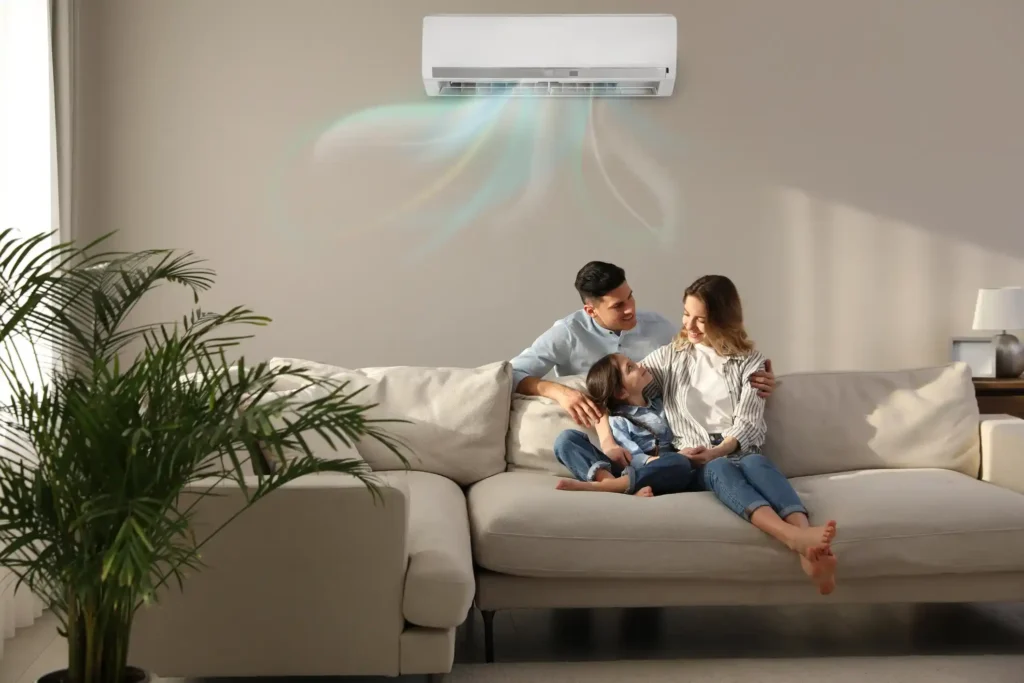 A family sitting in a sofa set with a ductless AC above their head