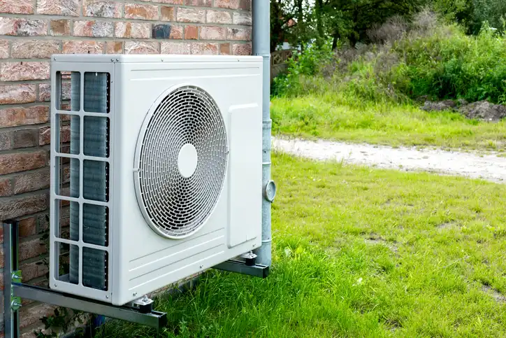 An air conditioning unit is installed outside a brick building.