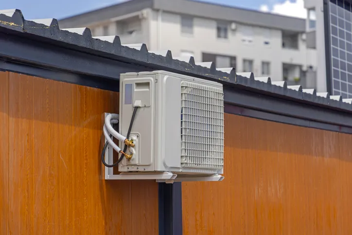 An outdoor air conditioner unit mounted on the side of a building.