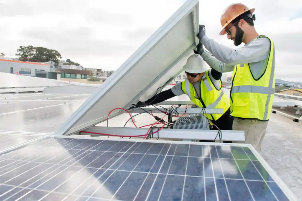 Two men installing solar panels on rooftop.