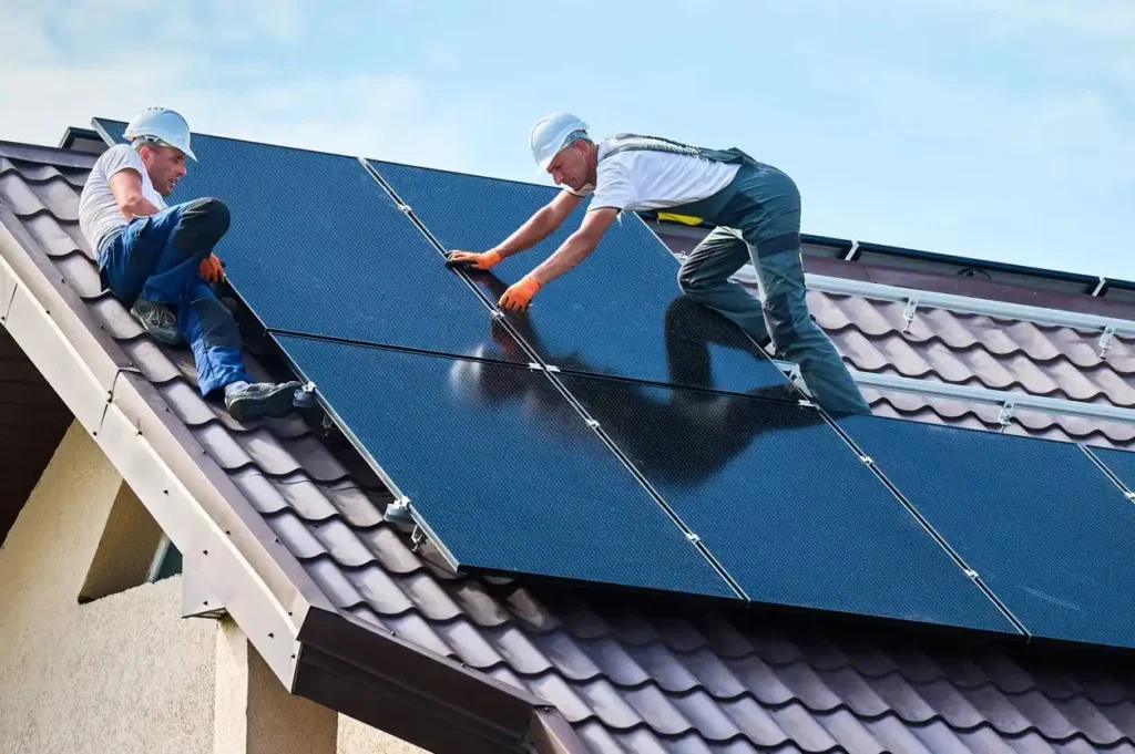 Two technician wearing white hard hat climbing in roof to clean the solar panels