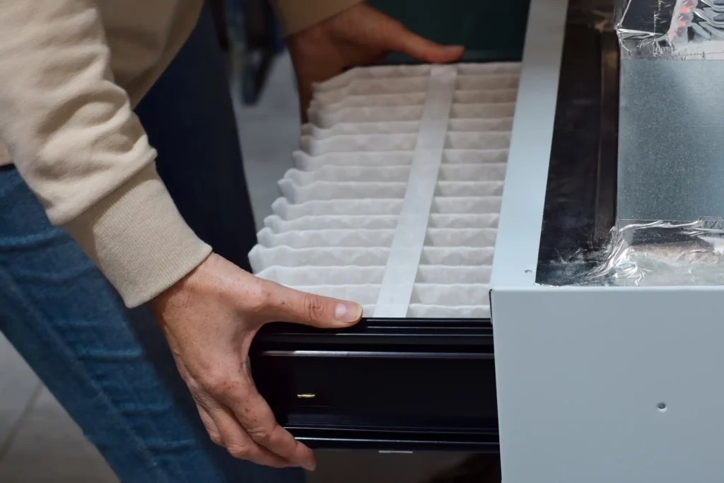 Hand changing air filter in HVAC unit